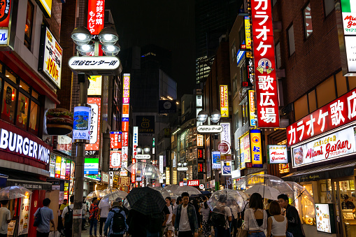 busy crowded shibuya street with various shop signs and logos lit up at night. Taken in Tokyo, Japan on June 29th 2019