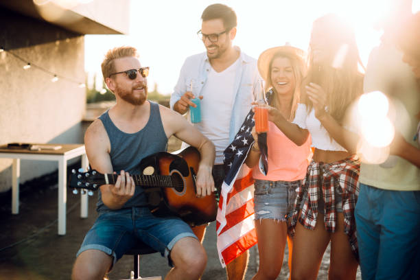 istock Young friends having fun at a rooftop party, playing the guitar, singing, dancing and drinking 1160549712