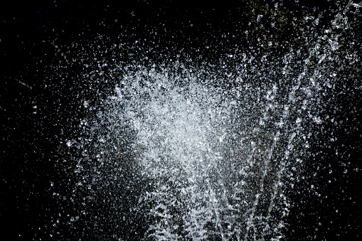 Water sprays and splashes on black background. Jets and drops of fountain isolated image