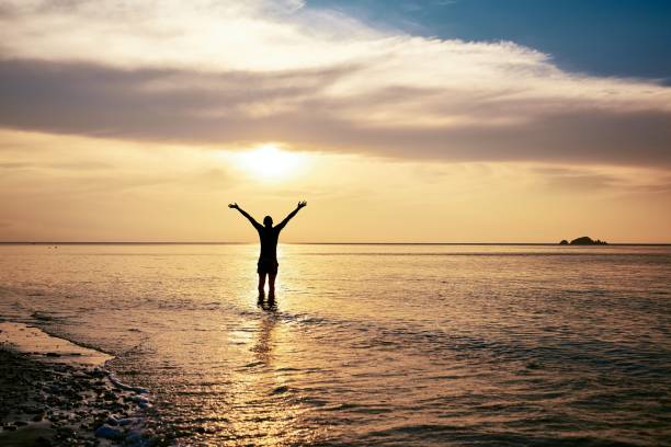 istock Happy man with arms outstretched standing in sea 1160555245
