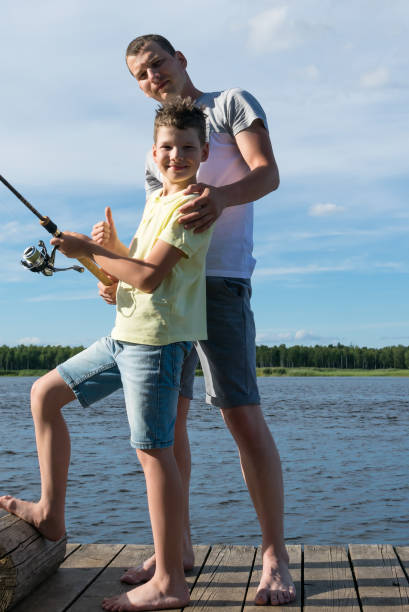 istock dad and son catch fish by spinning on the lake 1160556880