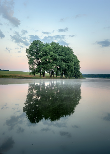 Colorful sunrise on a small lake near the village background