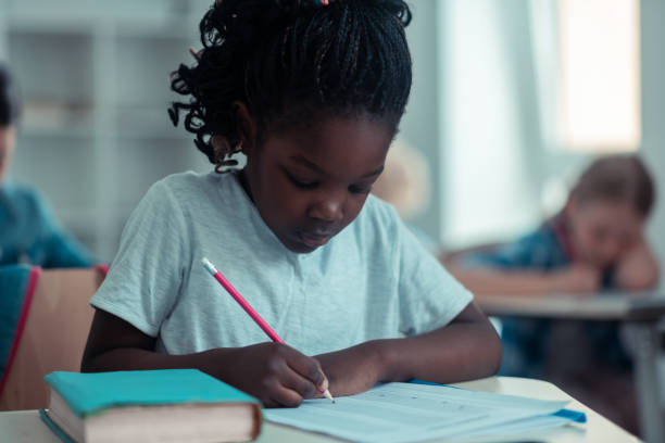 istock Focused little girl writing her school test. 1160558980
