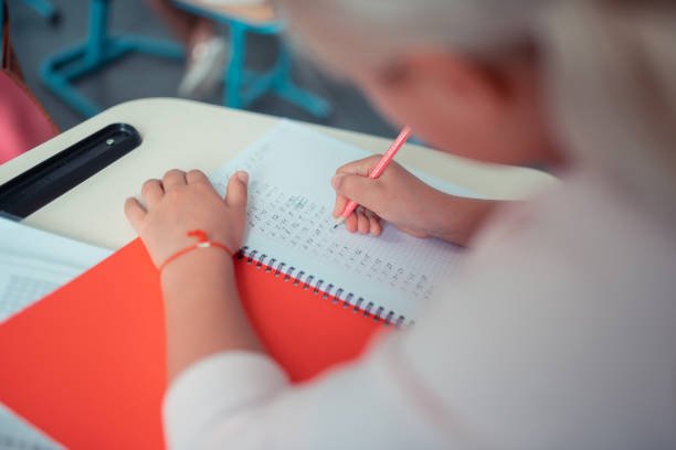istock Schoolgirl doing sums in her red copybook. 1160558996