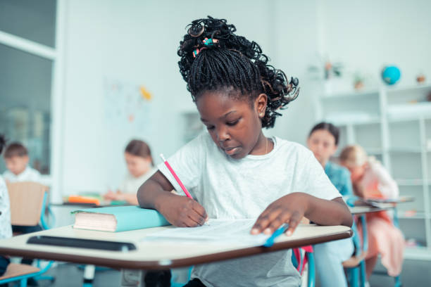 istock Schoolgirl doing sums with concentrated face at the test . 1160559002