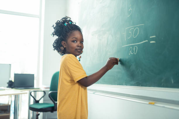 fille d'école pensant quoi écrire sur un tableau noir. - early childhood education photos et images de collection