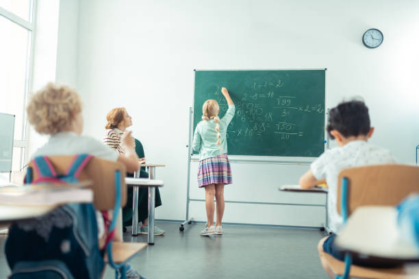 istock School girl speaking and writing in front of the class. 1160559012
