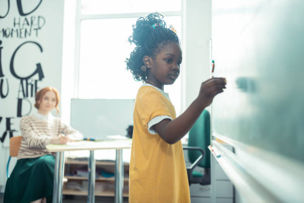 istock Thoughtful girl going to write on a blackboard. 1160559015
