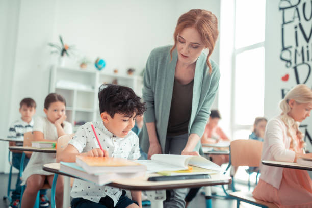 istock Pupil reading his homework to the teacher. 1160559180