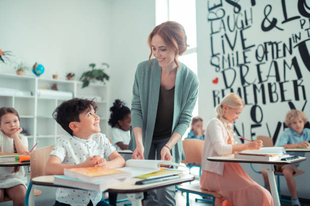 istock Cheerful pupil smiling to his kind teacher. 1160559181