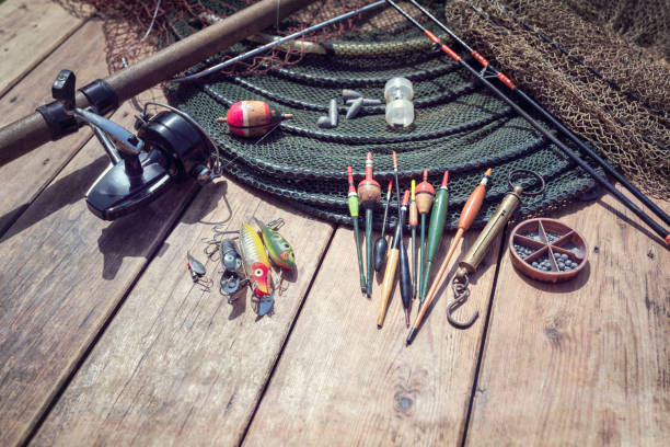 Fishing rod, reel, floats and tackle background on wooden jetty by river