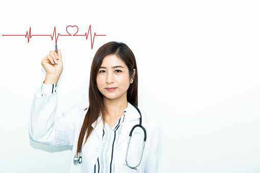 Beautiful woman doctor hanging stethoscope and drawing heartbeat symbol with white background.