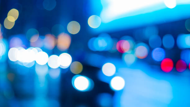 Night road with car lights and lamplight - blurred bright background with blue hues