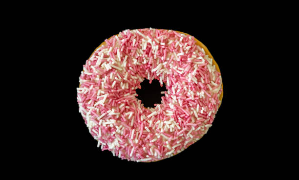 istock Doughnut with pink and white sprinkles isolated on black color background. Top view 1160561301