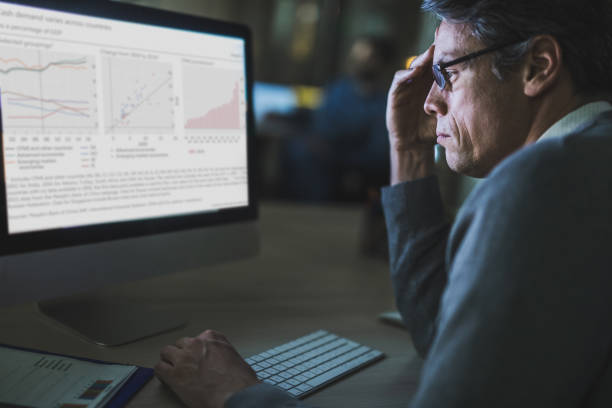 istock Profile view of thoughtful businessman analyzing charts on a computer in the office. 1160561439