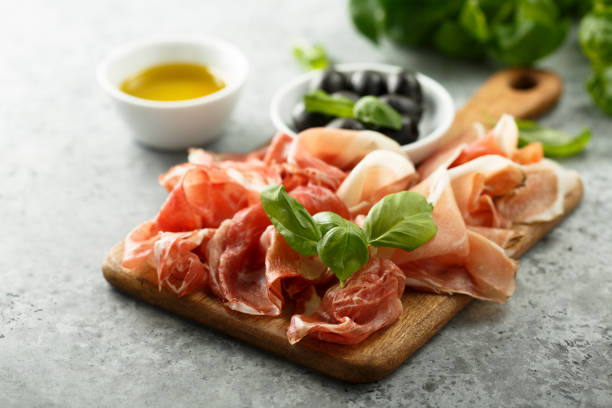 Charcuterie board Charcuterie board with fresh basil prosciutto stock pictures, royalty-free photos & images