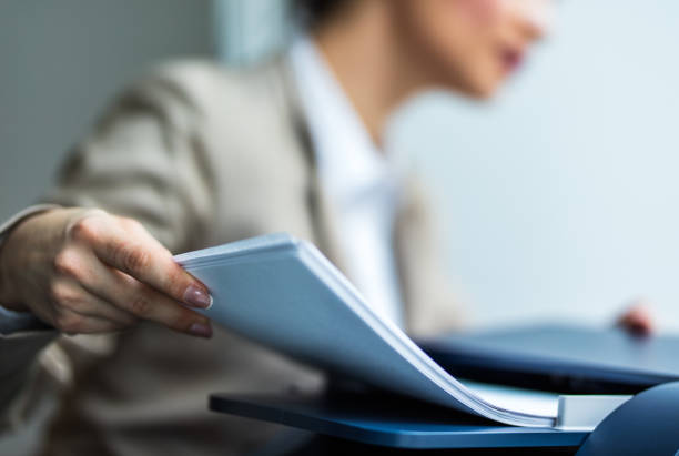 Close up of unrecognizable secretary working on copy machine. Close up of unrecognizable businesswoman faxing bunch of papers over fax machine in the office. computer printer stock pictures, royalty-free photos & images