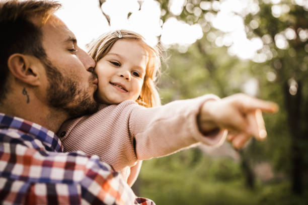 istock Affectionate single father kissing his small daughter in nature. 1160565407