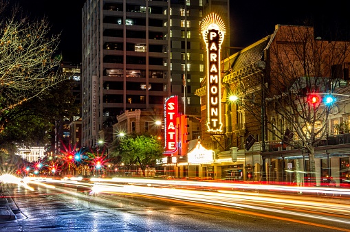 Austin, TX—January 9, 2019; streaks of light from cars in motion on Congress Ave in downtown pass in front of the State and Paramount Theaters with their neon signs lining the road.