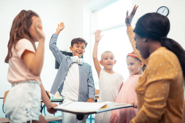 istock Children and teacher raising their hands while having fun together 1160569896