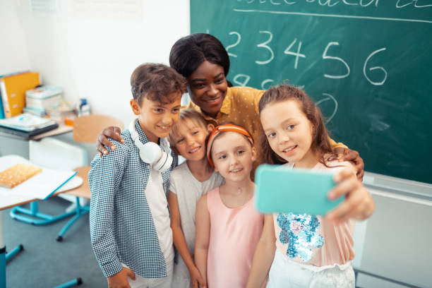 istock Dark-haired girl making selfie with her teacher and classmates 1160569914