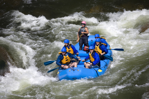 A group of 5 men and women, with a guide, white water rafting on the Arkansas River in Colorado.