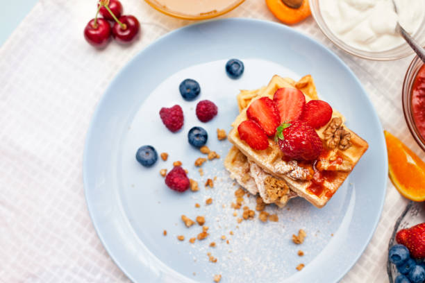 breakfast - waffles with powdered sugar, strawberries and walnut fruits