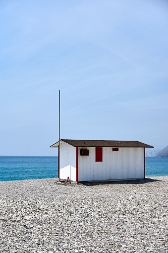 small white hut on a pebble beach with the sea in front of it