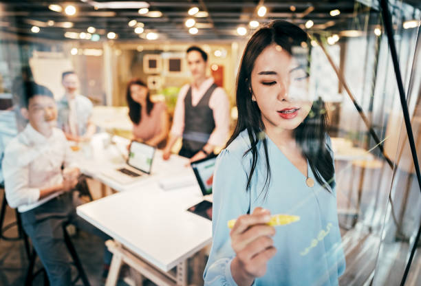 mulher de negócios asiática que apresenta suas idéias para o desenvolvimento da companhia - business development - fotografias e filmes do acervo