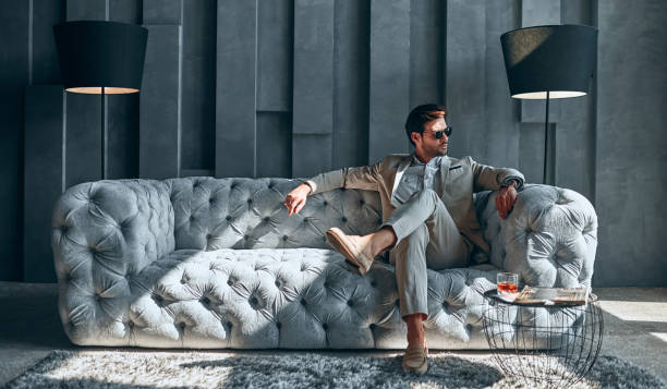 Stylish man at home Handsome stylish man in beige suit at home sitting on sofa. rich man stock pictures, royalty-free photos & images