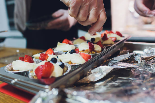 A chef decorates many plates of cake.