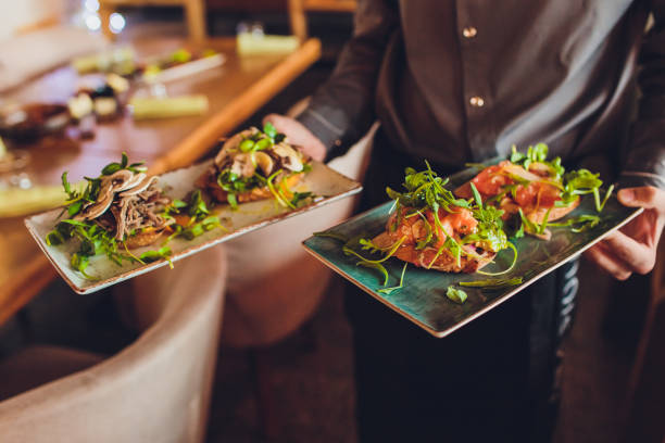 dos platos de carne con hojas de ensalada y ensalada de verano en la mano de camarero. - aperitivo plato de comida fotografías e imágenes de stock