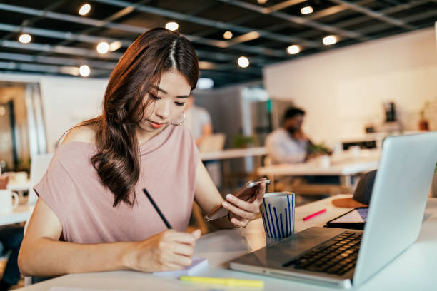 Young woman using laptop and smart phone in open co-working office