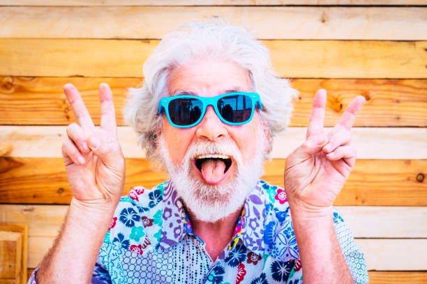 Crazy and happy active young and youth senior man making fun expression at the camera with winner hands - white hair and no limit age for old people love to play - happiness lifestyle for mature retired