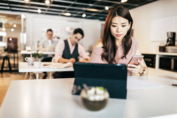 istock Young woman using digital tablet and smart phone in open co-working office 1160579555
