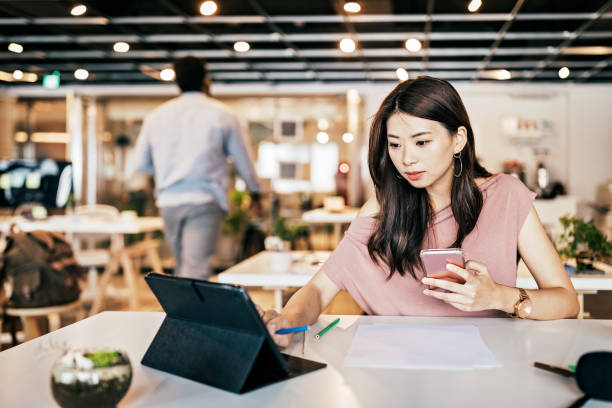 istock Young woman using digital tablet and smart phone in open co-working office 1160579714