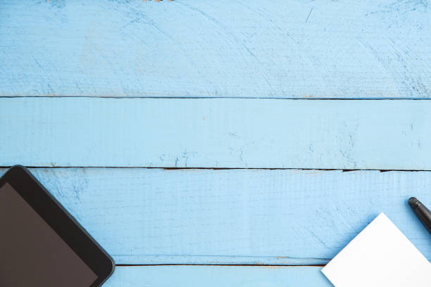 czarny tablet, mały notatnik i czarny długopis na niebieskim drewnianym tle. widok z góry - multimedia digital tablet information medium small zdjęcia i obrazy z banku zdjęć