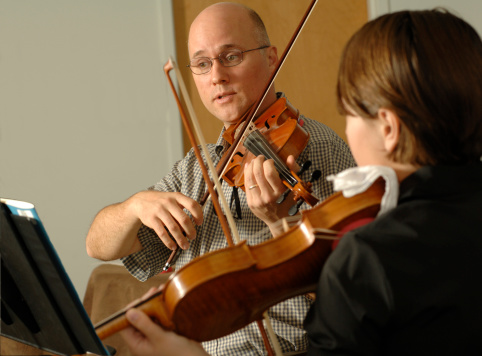 a violin teacher gives a lesson