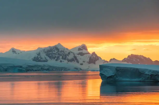 Beautiful light of the sunset on the landscape of Antarctica with mountains, glaciers and icebergs
