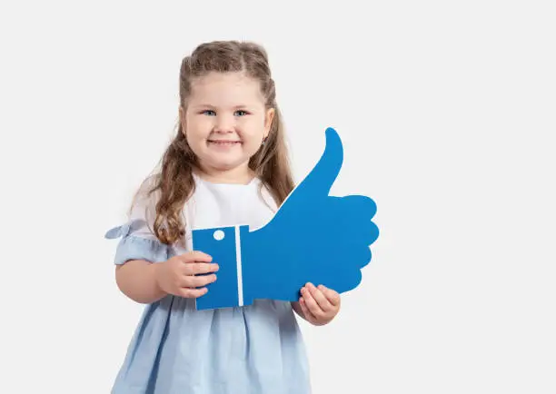 Photo of Little cute girl holding cartoon like on grey background.Social media concept.