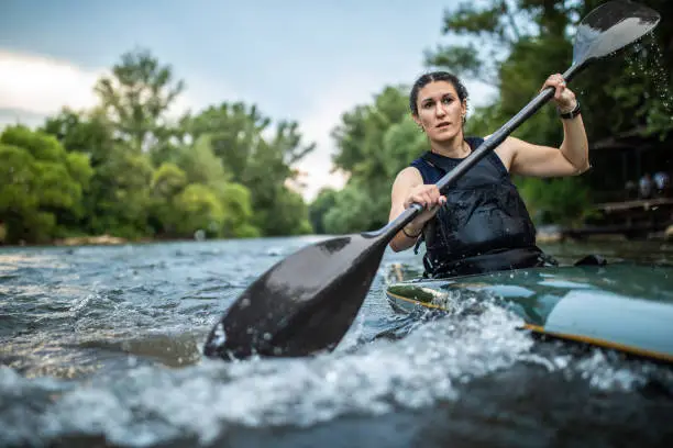 Portrait of Strong sport woman kayaking on speed river , holding oar and enjoying sport training
