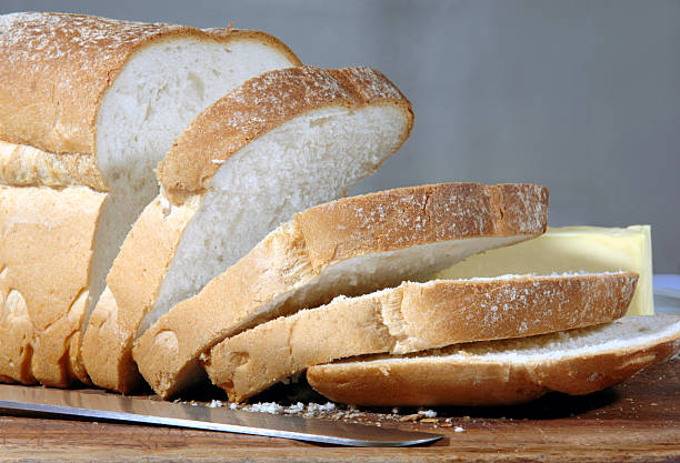 Loaf of bread cut into slices with bread knife stock photo