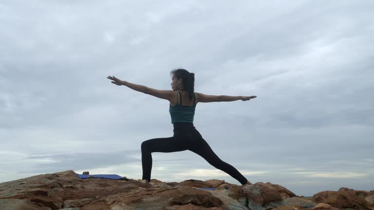 4k,Asian yoga woman teacher helps young woman to practise yoga on the hill near the tropical beach.