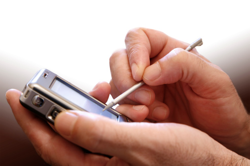 Male hand with digitized pen, touching the screen of a PDA.