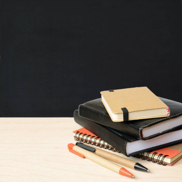 istock Notebooks and pens on wooden table with school black board 1160601188