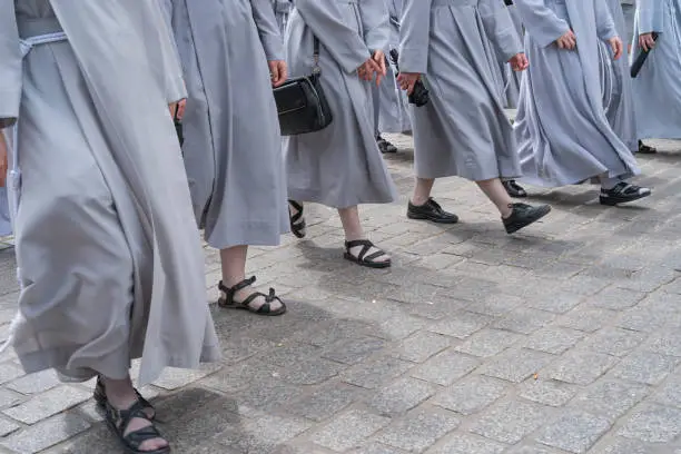 Nuns in grey habits walking on a stone cobbled street.