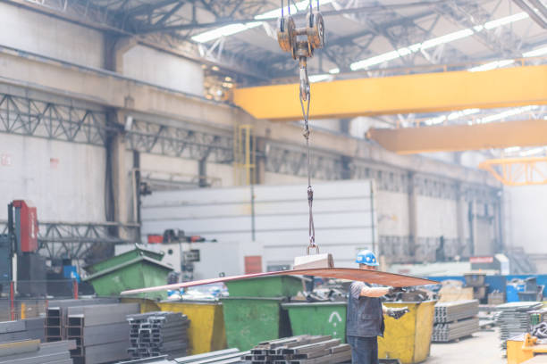 Overhead crane with magnetic grippers lifting steel sheets