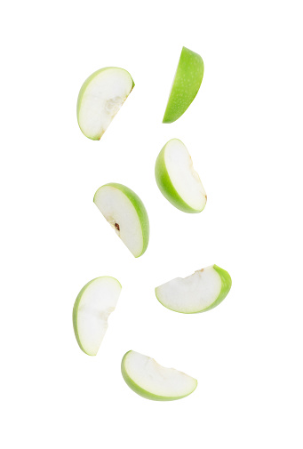 Slice ripe green apple falling isolated on white background with clipping path.