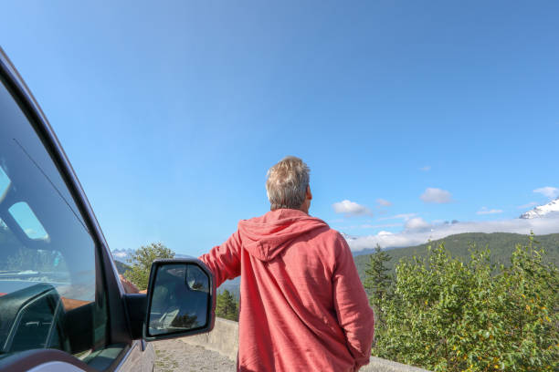 istock Mature man leans against car on a road 1160605549