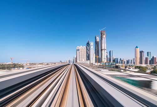 United Arab Emirates, Dubai, View from inside train driving on tracks on Dubai Metro public transit system with downtown skyline in distance.